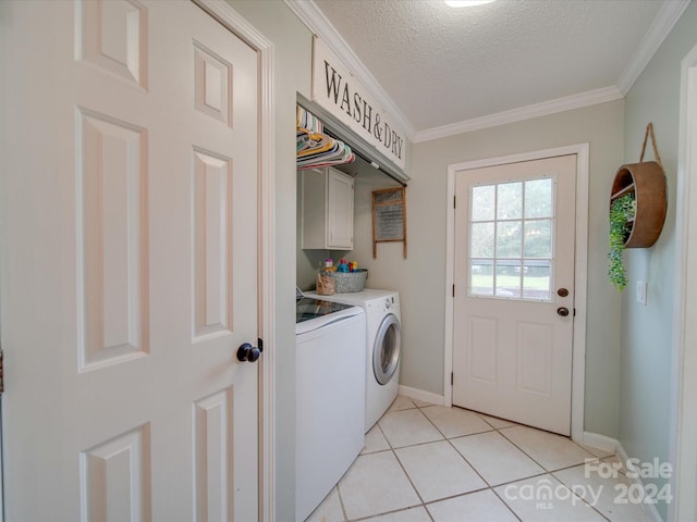 laundry area featuring cabinets, a textured ceiling, washer and dryer, light tile patterned floors, and ornamental molding