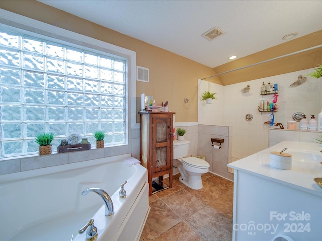 bathroom with vanity, a tub to relax in, toilet, and tile walls