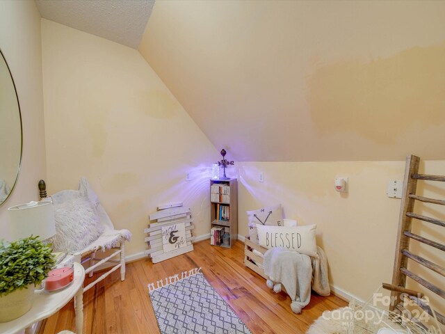 sitting room featuring baseboards, vaulted ceiling, and light wood-style flooring
