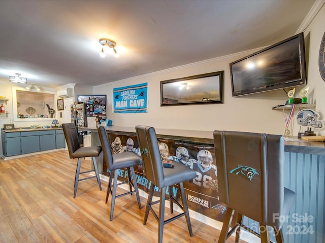bar featuring ornamental molding, a bar, light wood finished floors, and a wall unit AC