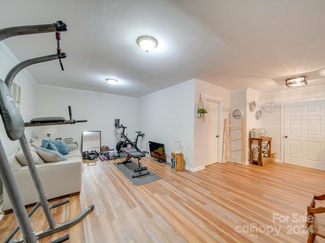 exercise room featuring baseboards, ornamental molding, and wood finished floors