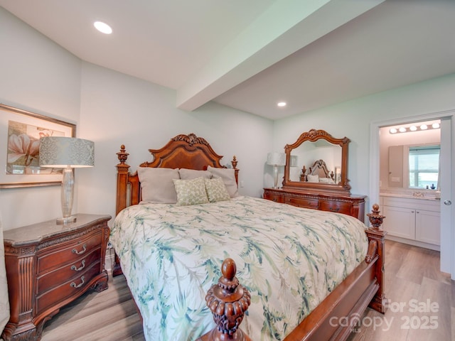 bedroom with connected bathroom, beamed ceiling, and light wood-type flooring