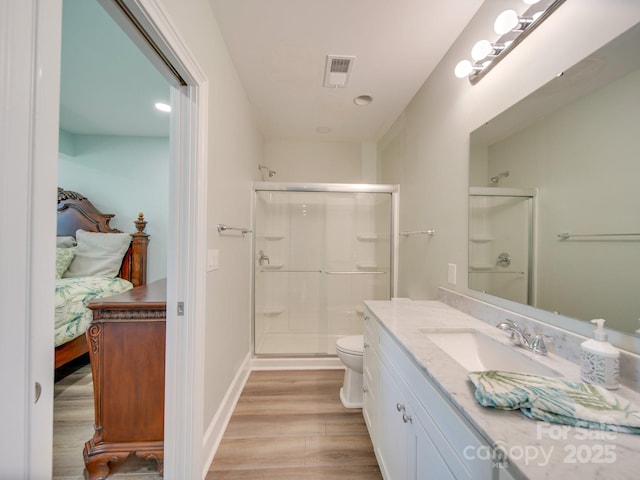 bathroom with hardwood / wood-style floors, toilet, walk in shower, and vanity