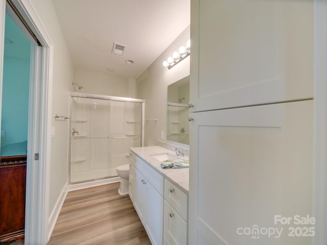 bathroom featuring vanity, toilet, hardwood / wood-style floors, and a shower with door