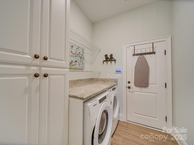 laundry area featuring light wood-type flooring, cabinets, and washer and dryer