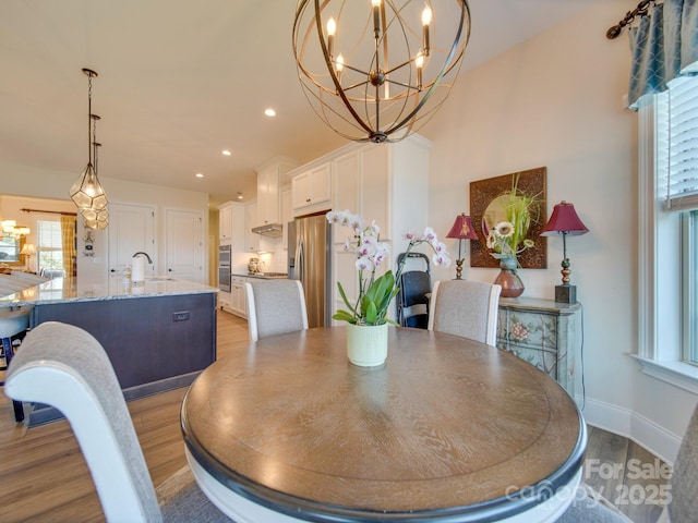 dining space with sink, light hardwood / wood-style flooring, and an inviting chandelier