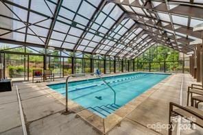 view of pool with glass enclosure and a patio area