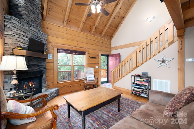 living room featuring wood walls, a fireplace, high vaulted ceiling, hardwood / wood-style flooring, and ceiling fan