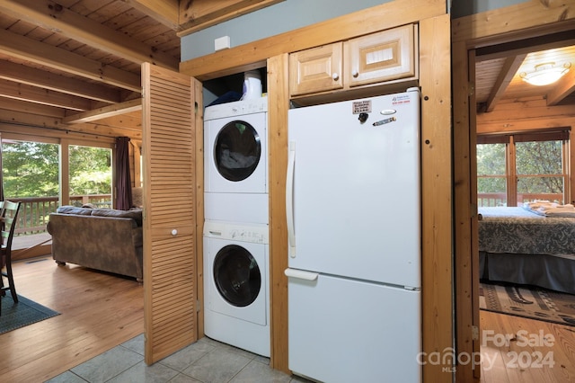 clothes washing area featuring light hardwood / wood-style flooring, wooden ceiling, and stacked washer / dryer