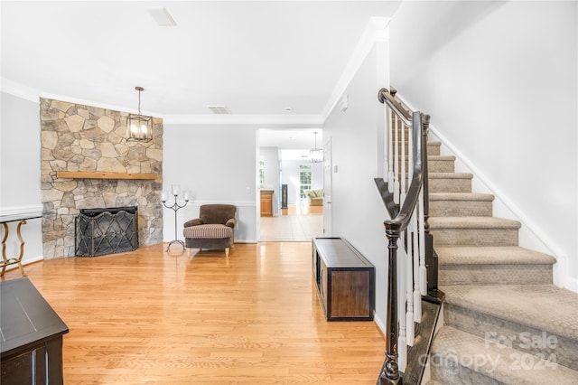 living room featuring crown molding, stairs, a notable chandelier, and light wood-type flooring