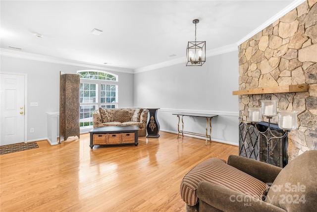 living room with light hardwood / wood-style flooring, an inviting chandelier, a fireplace, and crown molding