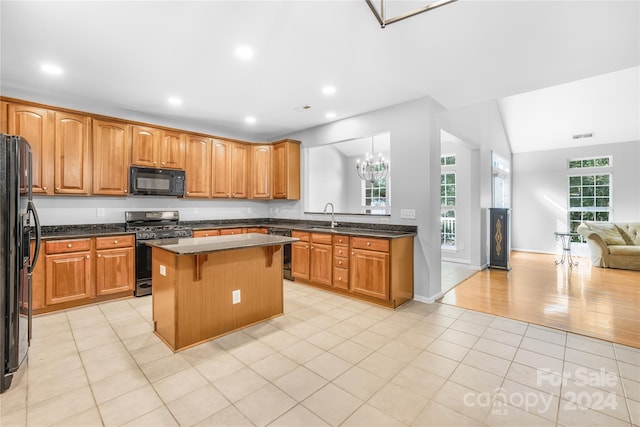 kitchen featuring light tile patterned flooring, sink, vaulted ceiling, a kitchen island, and black appliances