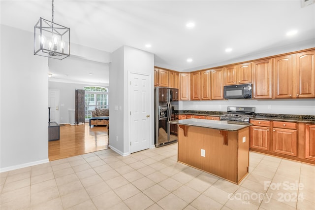 kitchen featuring a center island, a breakfast bar area, a notable chandelier, black appliances, and decorative light fixtures