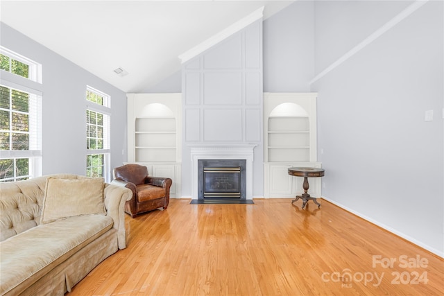 living area with light wood-style floors, built in features, a fireplace, baseboards, and visible vents