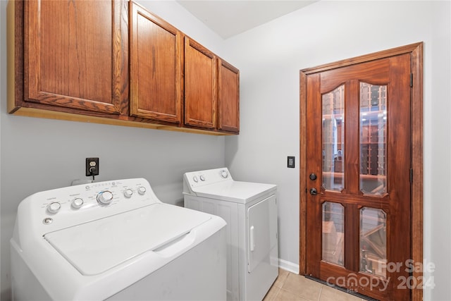 laundry area featuring light tile patterned floors, washer and dryer, and cabinets