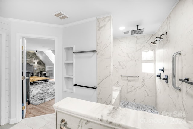 bathroom with ornamental molding, built in features, hardwood / wood-style flooring, and tiled shower