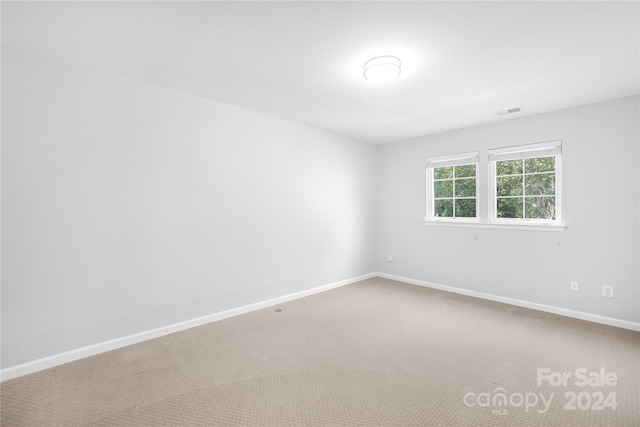 carpeted spare room with visible vents and baseboards