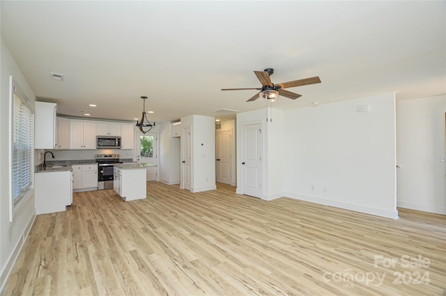 kitchen with appliances with stainless steel finishes, white cabinetry, a center island, light hardwood / wood-style flooring, and sink