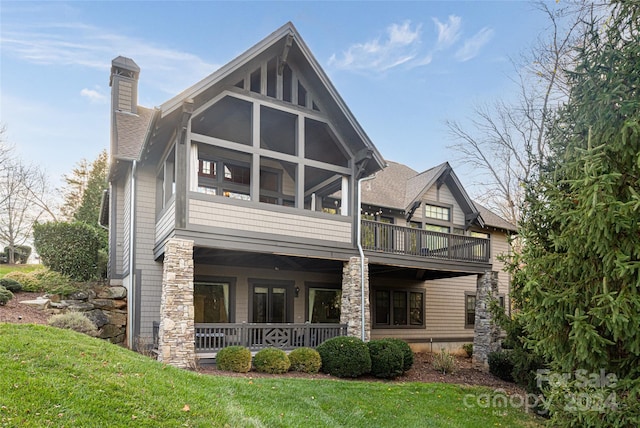 back of property with a lawn and a sunroom