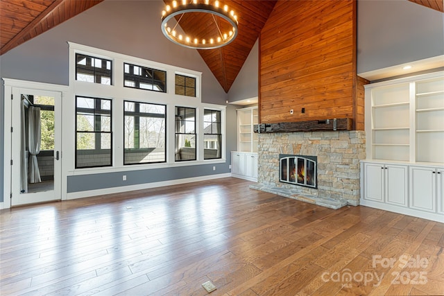 unfurnished living room featuring built in shelves, wooden ceiling, and a towering ceiling