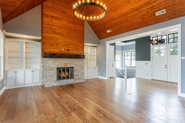 unfurnished living room with an inviting chandelier, hardwood / wood-style floors, a fireplace, and high vaulted ceiling