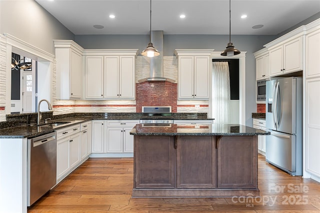 kitchen with pendant lighting, decorative backsplash, dark stone counters, stainless steel appliances, and wall chimney range hood