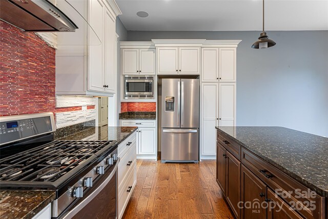 kitchen with white cabinetry, appliances with stainless steel finishes, backsplash, and light hardwood / wood-style flooring