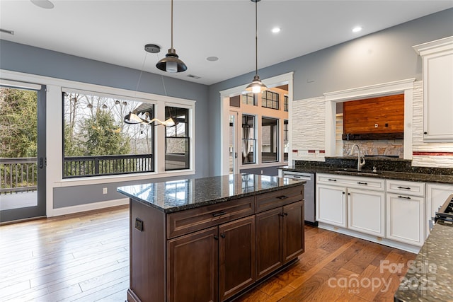 kitchen with dark hardwood / wood-style flooring, dishwasher, pendant lighting, dark stone counters, and white cabinets