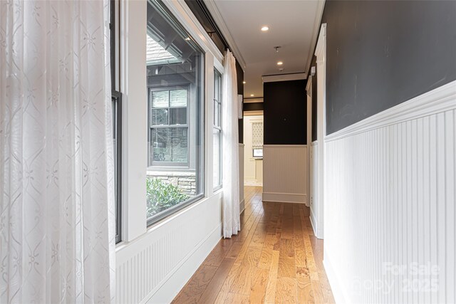 hall with crown molding, a barn door, and light wood-type flooring