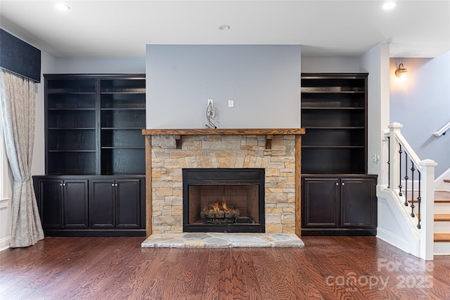 unfurnished living room featuring dark wood-type flooring and a stone fireplace