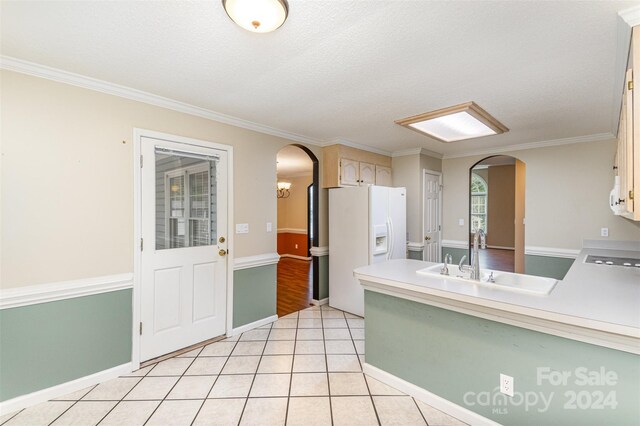 kitchen with light tile patterned floors, ornamental molding, sink, a textured ceiling, and white refrigerator with ice dispenser