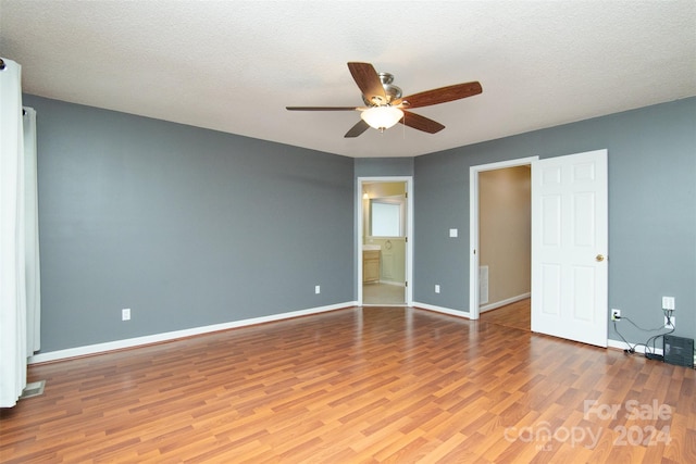 unfurnished bedroom featuring light wood-type flooring, ceiling fan, connected bathroom, and a textured ceiling