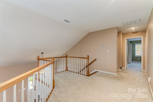 hall with lofted ceiling and light colored carpet