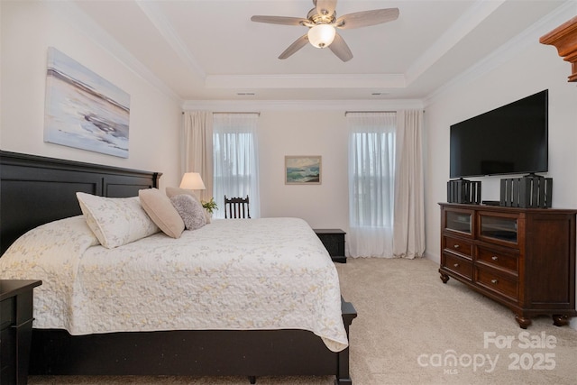 bedroom with ceiling fan, crown molding, a tray ceiling, and light carpet