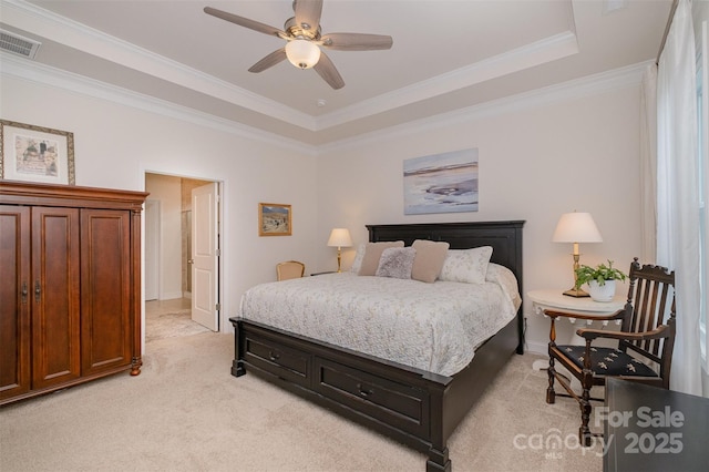 carpeted bedroom with crown molding, a tray ceiling, and ceiling fan