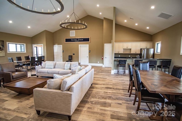 living room with a chandelier, light hardwood / wood-style flooring, and high vaulted ceiling