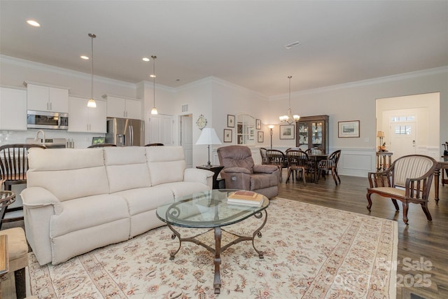 living room featuring crown molding, light wood-type flooring, and a notable chandelier