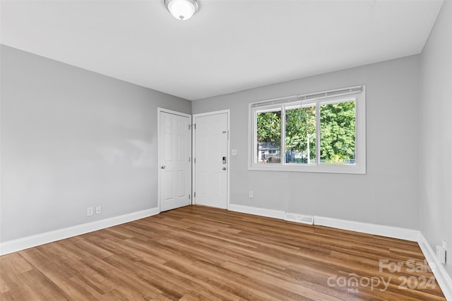 unfurnished room featuring wood finished floors, visible vents, and baseboards