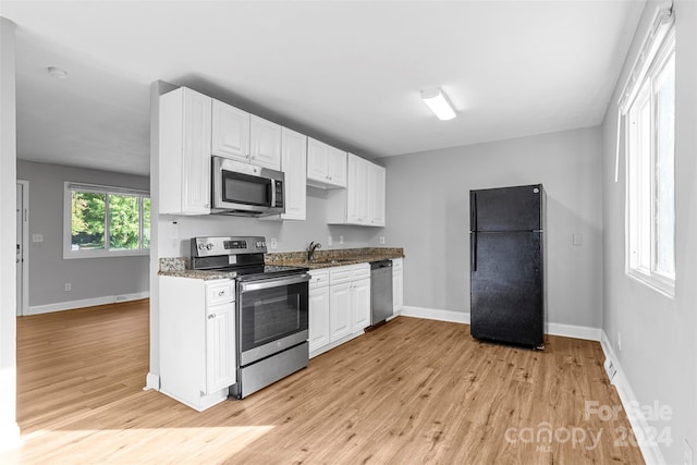 kitchen featuring baseboards, light wood-style flooring, a sink, white cabinets, and appliances with stainless steel finishes