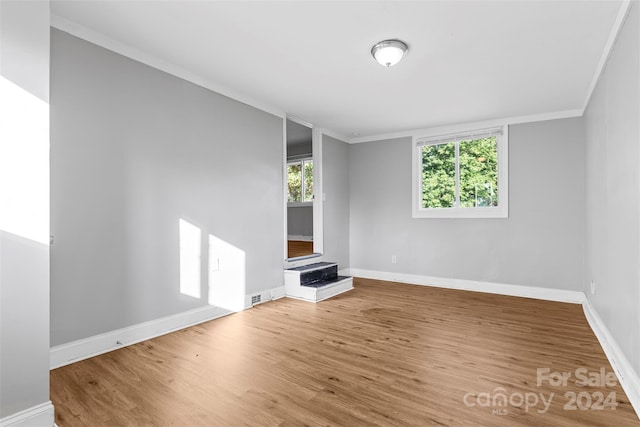 unfurnished living room featuring hardwood / wood-style floors, a fireplace, and crown molding