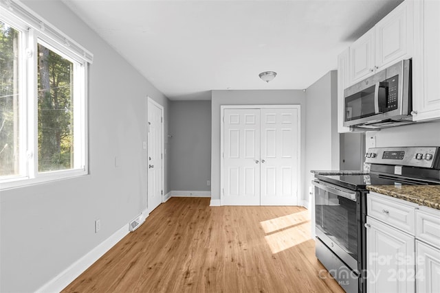 kitchen featuring appliances with stainless steel finishes, a wealth of natural light, white cabinets, and light hardwood / wood-style floors