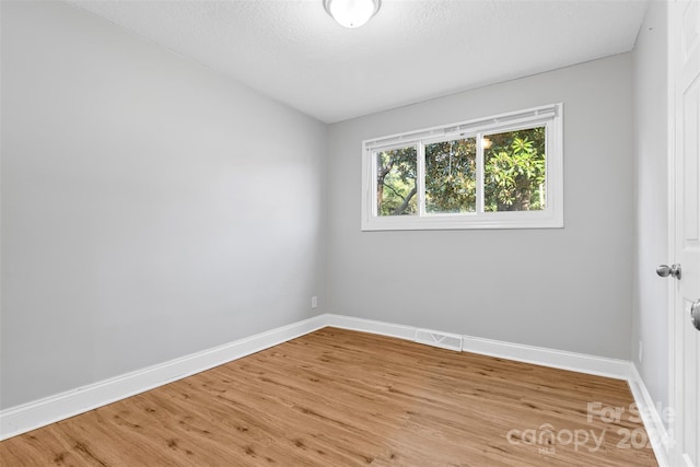 unfurnished room with visible vents, baseboards, a textured ceiling, and light wood-style flooring