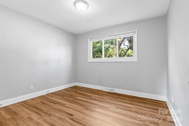 unfurnished room featuring visible vents, a textured ceiling, baseboards, and light wood-style floors