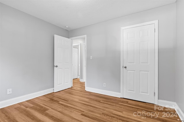 unfurnished bedroom with a textured ceiling and light wood-type flooring