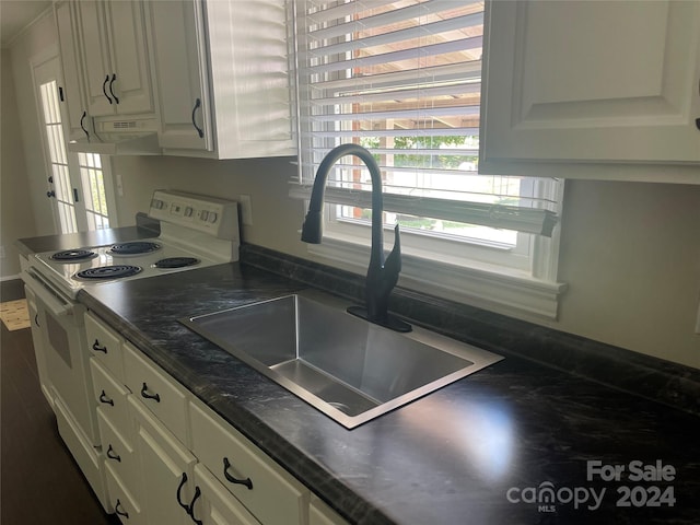 kitchen featuring white electric range, white cabinetry, exhaust hood, and sink