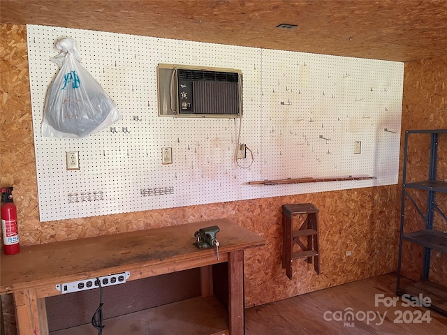 interior space featuring hardwood / wood-style flooring, a workshop area, and a wall mounted air conditioner