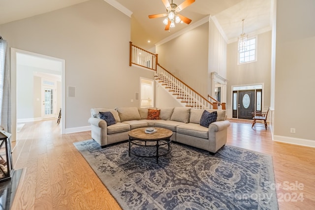 living room featuring crown molding, high vaulted ceiling, light hardwood / wood-style floors, and ceiling fan with notable chandelier