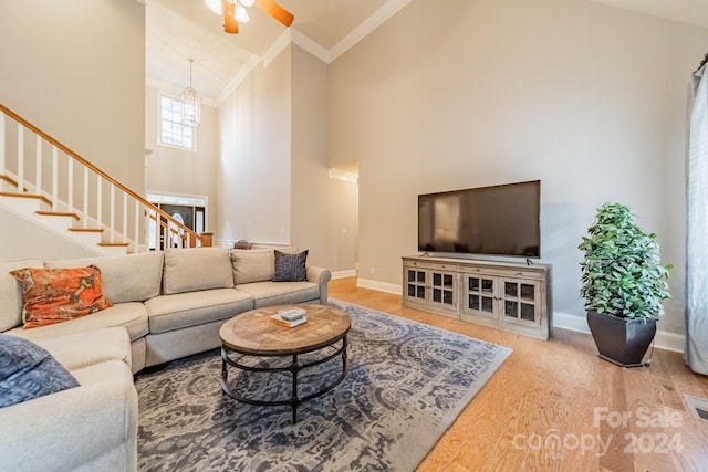 living room with hardwood / wood-style floors, ceiling fan, crown molding, and high vaulted ceiling