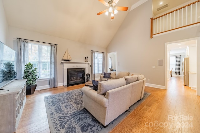 living room with ceiling fan, high vaulted ceiling, and light wood-type flooring