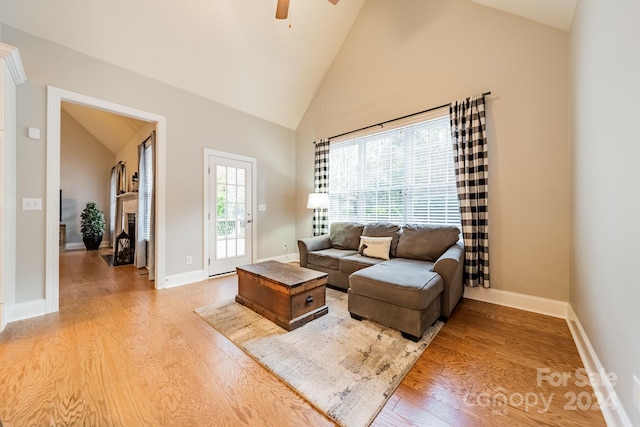 living room featuring light hardwood / wood-style floors, high vaulted ceiling, and ceiling fan